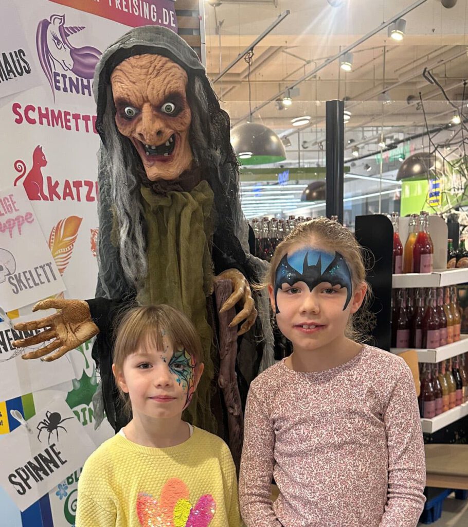 Zwei Kinder stehen neben eine Hexenpuppe